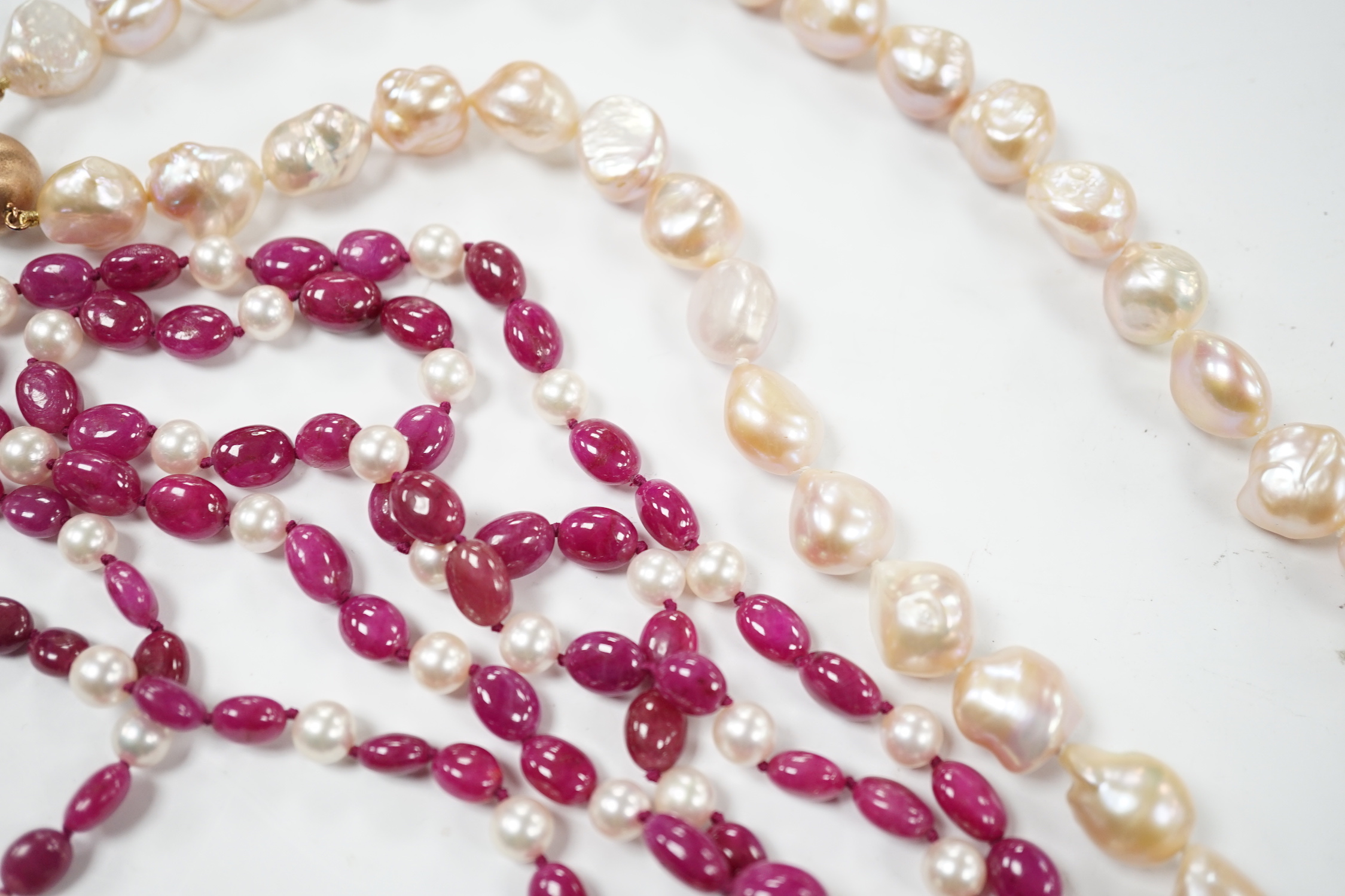 A modern cultured pearl and polished ruby? bead necklace, with two stone diamond chip set 750 clasp, 166cm and a modern baroque freshwater? pearl necklace with 925 clasp.